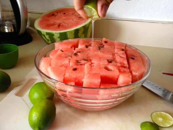 Bowl of watermelon with a lime being squeezed on top of it